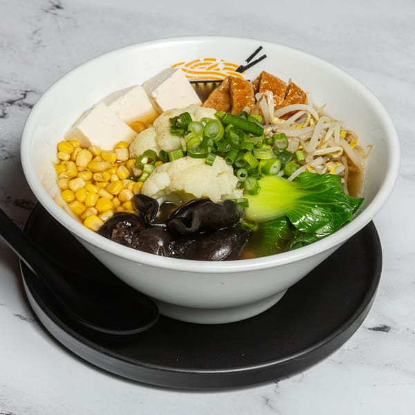 A bowl of Ramen Lab Eatery ramen with tofu, corn, cauliflower, bok choy, and mushrooms.