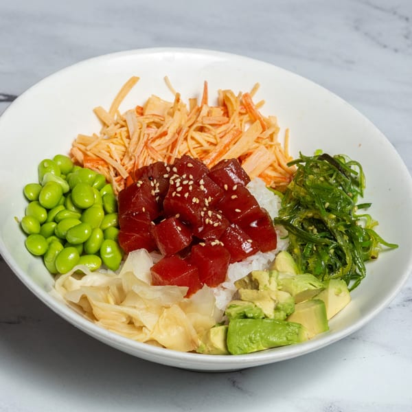 A colorful poke bowl with tuna, edamame, seaweed salad, avocado, and imitation crab.
