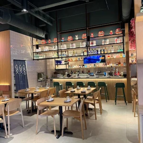 Interior of Ramen Lab Eatery with dining tables, chairs, and a well-stocked bar area.