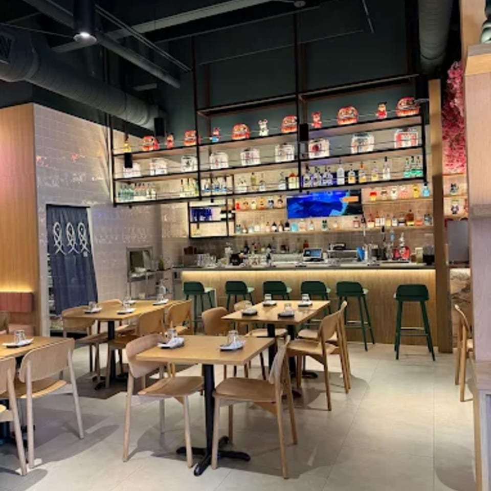 Interior of Ramen Lab Eatery with dining tables, chairs, and a well-stocked bar area.